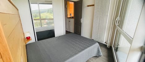A bedroom with a bed, a window, and a radiator.