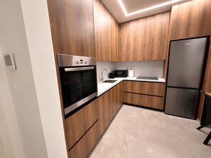 Een moderne keuken met houten kasten, een ingebouwde oven, een magnetron, een spoelbak en een koelkast.