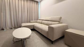 A modern living room with a sectional sofa, a round coffee table, and a side table.