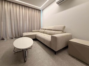 Een moderne woonkamer met een hoekbank, een ronde salontafel en een bijzettafeltje.