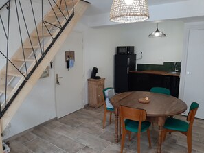 A dining area with a wooden table and chairs, a kitchen with a microwave, and a staircase. - Triplex at the base of the aerial cableway with parking (Ax-les-Thermes)