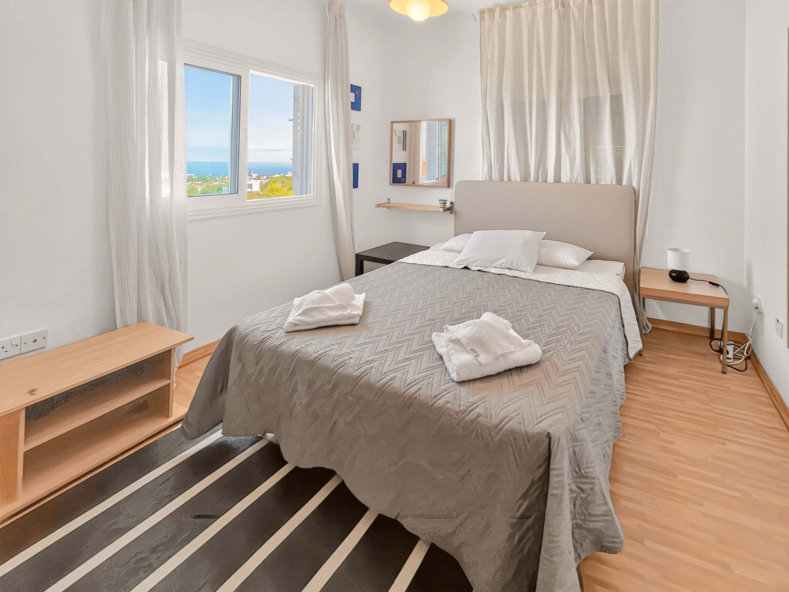 A hotel room with a bed, bedside table, and a view of the sea.