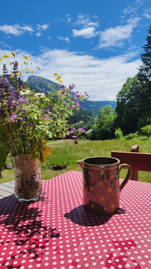 Et bord med dug med prikker, en vase med blomster og en pitcher med mønster.
