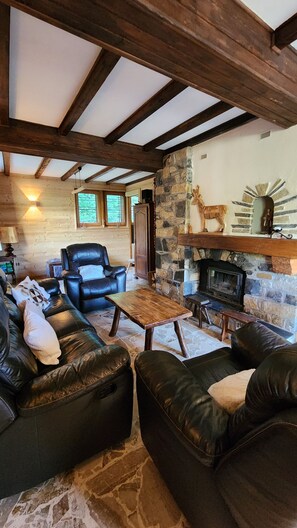 A cozy living room with leather sofas, a stone fireplace, and exposed wooden beams. - Quiet 8-person chalet with a magnificent view of the mountains, fireplace,garden (Abondance)