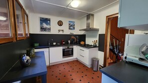 Cuina compacta amb fogó a gas, forn i rentamés. Hi ha elements decoratius a la paret i un rellotge. El terra té un disseny de rajoles estampades.