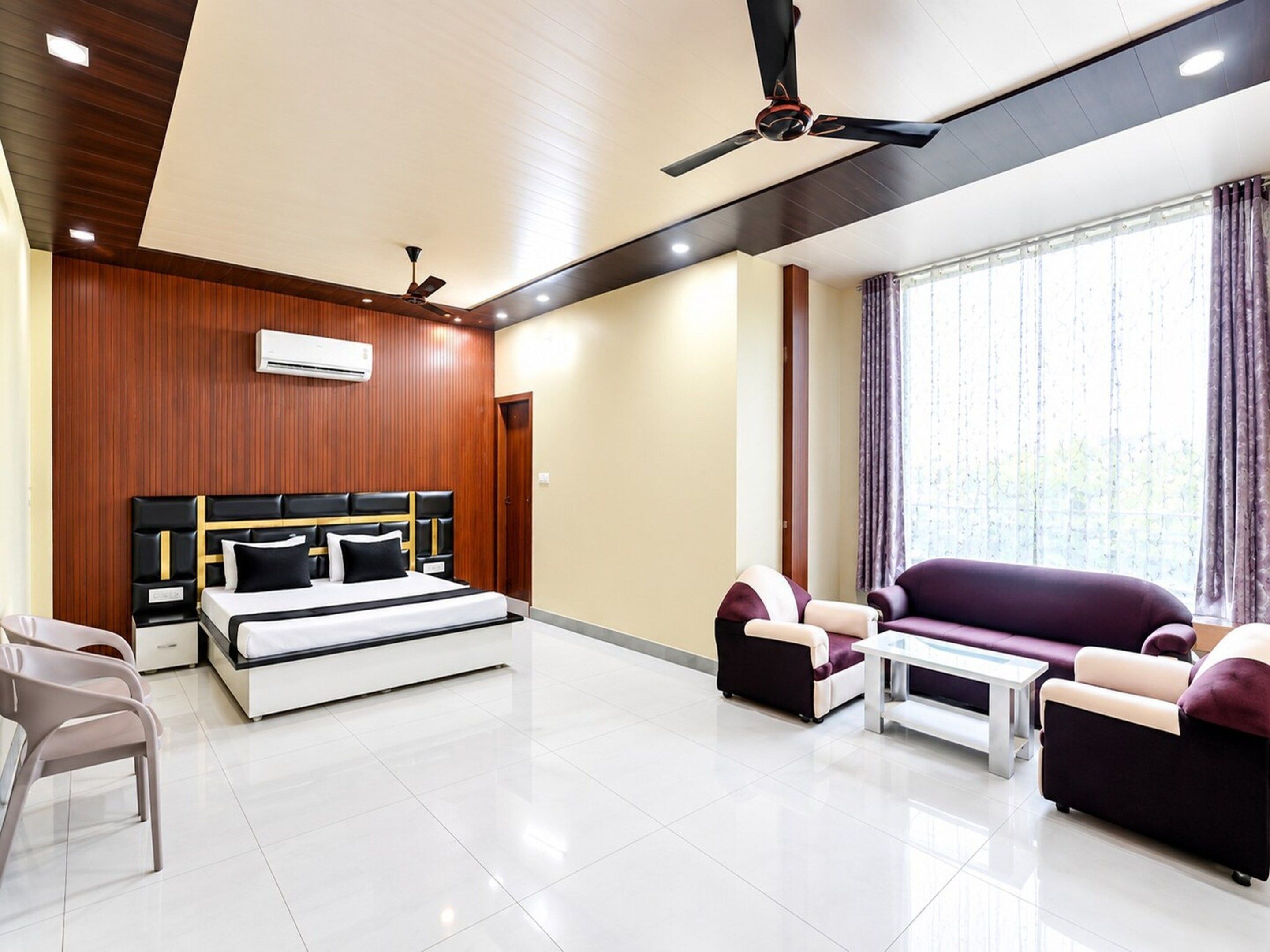 A modern hotel room with a bed, sofa, and a ceiling fan.