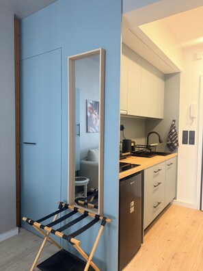 Una cocina compacta con encimera de madera, lavavajillas integrado y un pequeño comedor con mesa y sillas.