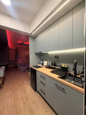 A compact kitchen with a wooden countertop, built-in cabinets, and a dishwasher. - The secret muse a metro hub apartment in the center of Thessaloniki (Thessaloniki)