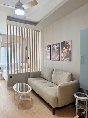 A modern living room with a sofa, two small tables, and a ceiling fan. - The secret muse a metro hub apartment in the center of Thessaloniki (Thessaloniki)