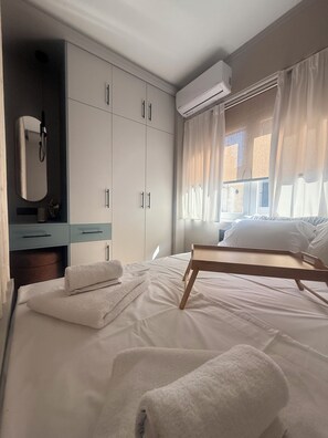 Una habitación de hotel con una cama, una mesita de noche, un espejo y un armario.