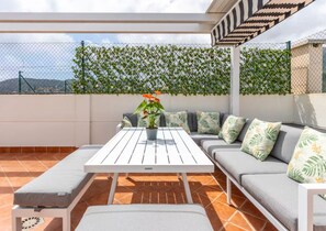 An outdoor seating area with a white table and grey cushioned sofa, a potted plant, and a patterned wall. - Penthouse with large private roof terrace - Calpe (Calp)