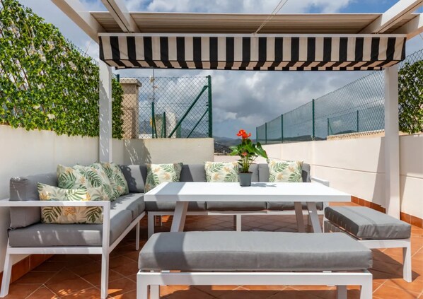 An outdoor patio with a white table and grey cushioned seating, surrounded by a white pergola and a chain-link fence. - Penthouse with large private roof terrace - Calpe (Calp)