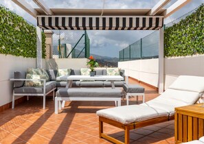 A rooftop terrace with a covered seating area, a table, and a lounge chair. - Penthouse with large private roof terrace - Calpe (Calp)