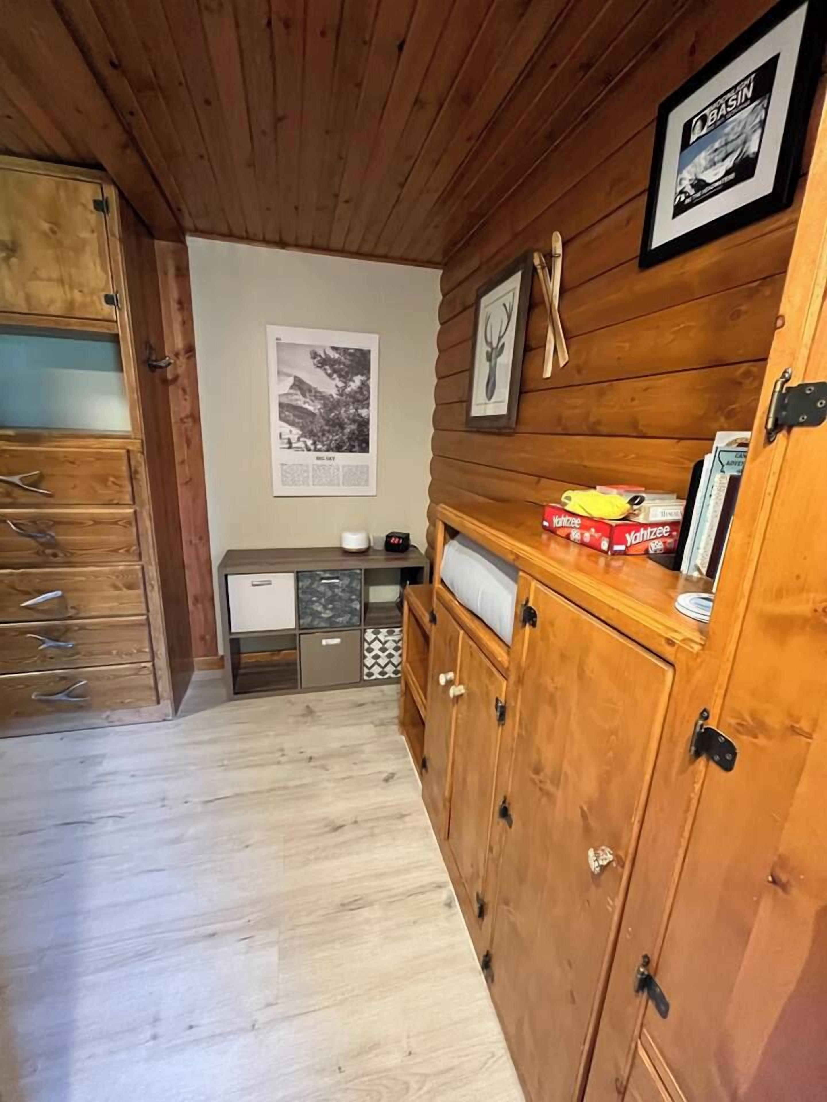 Een houten interieur met een kast, een ingelijste foto en een klein tafeltje met dozen.