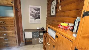 Een houten interieur met een kast, een ingelijste foto en een klein tafeltje met dozen.