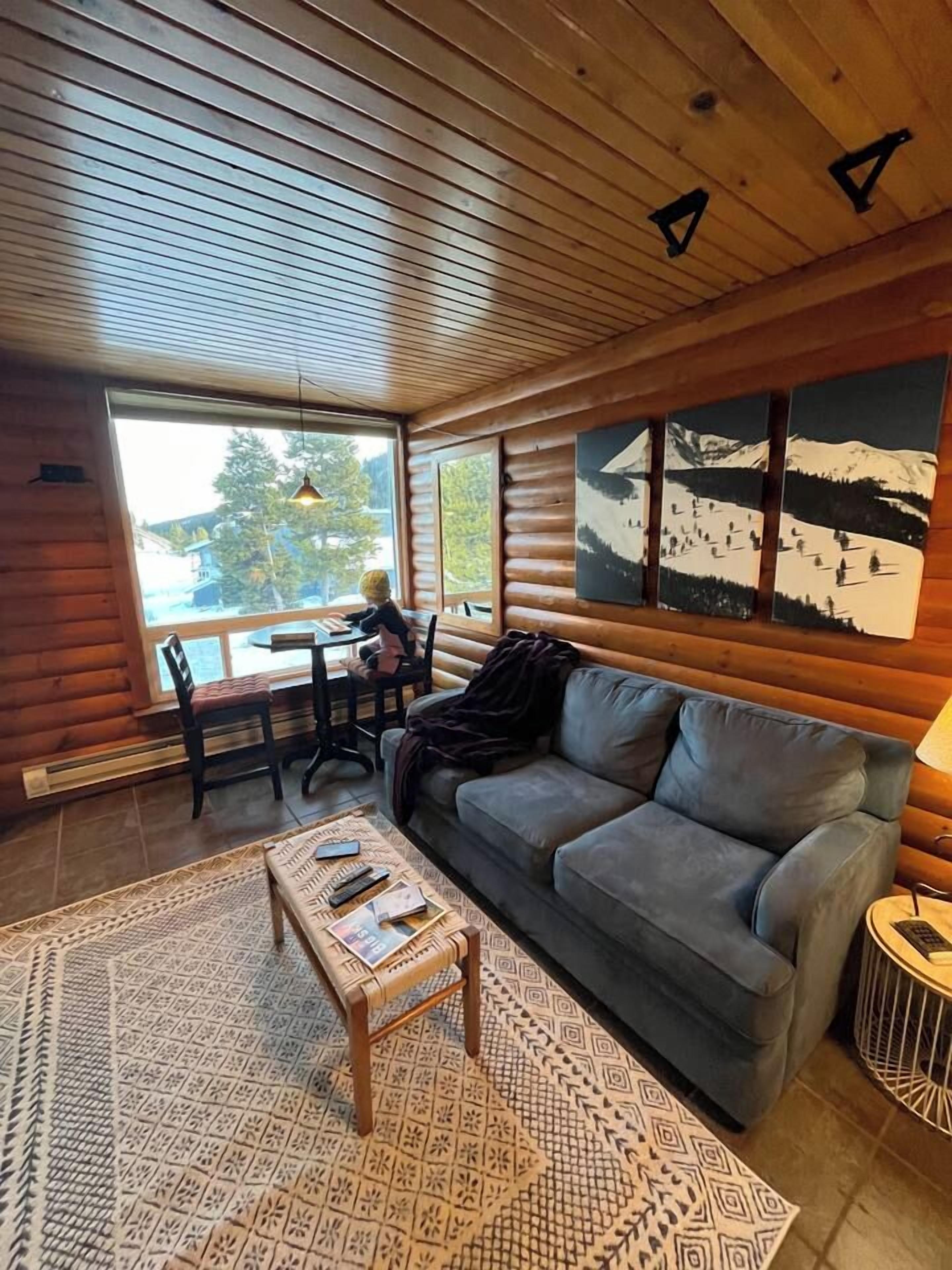 Interior acogedor de una cabaña con sofá, mesa de centro y comedor con sillas.