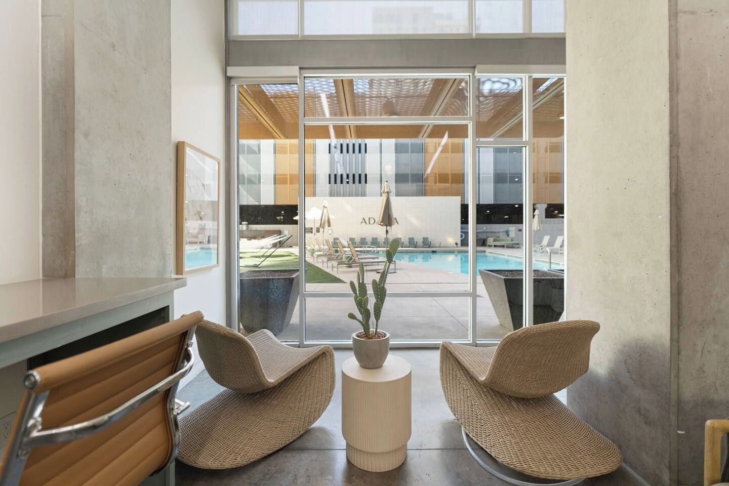 Interior moderno com vista para piscina, cadeiras de vime e uma planta em vaso.