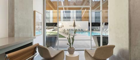 A modern interior with a pool view, wicker chairs, and a potted plant.