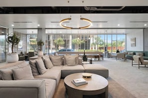 A modern lounge area with a sectional sofa, round coffee table, and seating arrangements. - Trendy 2BR w/ Pool, W/D & Wi-Fi | Arts District (Phoenix)