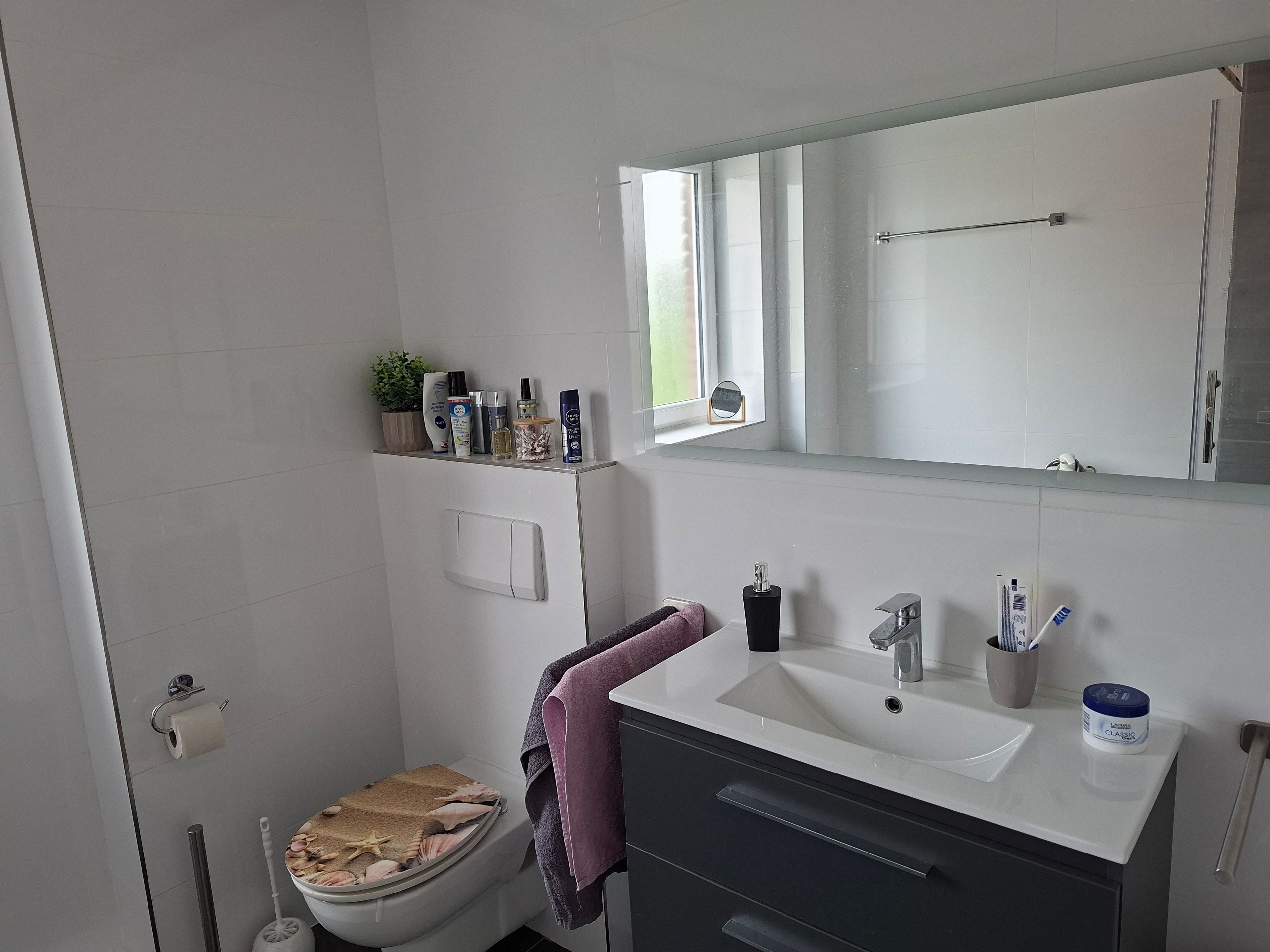 Ein modernes Badezimmer mit Toilette, Waschbecken und Spiegel.