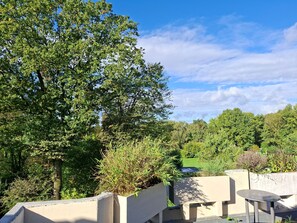 Eine Dachterrasse mit Betonpflanzgefäßen, einem Tisch und Stühlen.