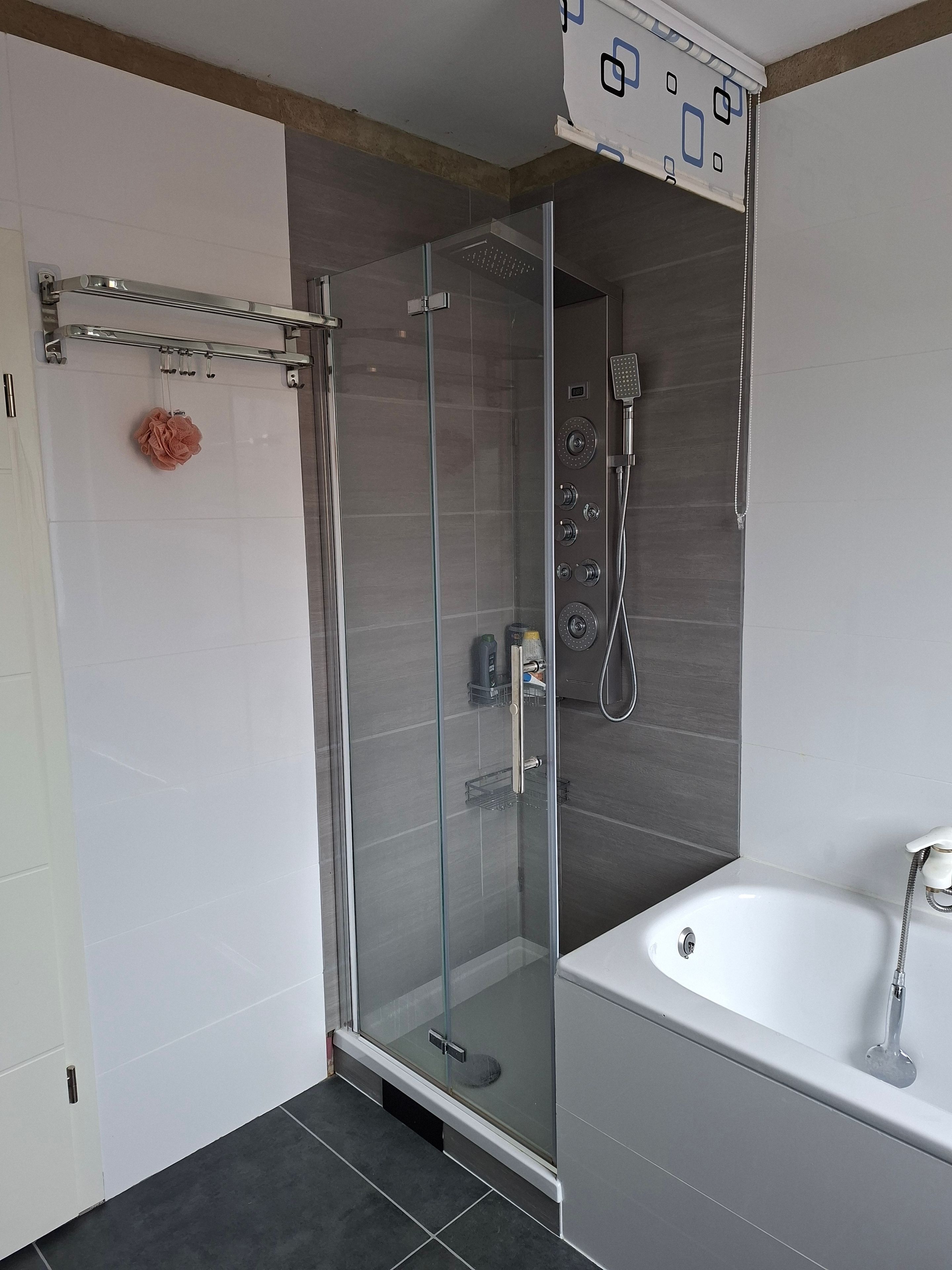 Une salle de bain moderne avec une douche à parois de verre, une baignoire blanche et un porte-serviettes.