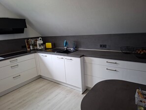 Eine moderne Küche mit weißen Schränken, einer grauen Arbeitsplatte und einer schwarzen Spritzschutzwand.