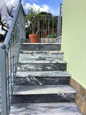 A staircase with marble steps and a metal railing, leading to a green wall. - Apartment 'Vista Mar' with Sea View, Wi-Fi and Air Conditioning (Lourinhã)