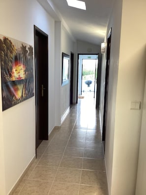 A hallway with tiled flooring, doors, and a framed picture on the wall. - Apartment 'Vista Mar' with Sea View, Wi-Fi and Air Conditioning (Lourinhã)