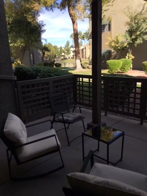 An outdoor seating area with two chairs and a small table, surrounded by a wooden fence and greenery. - Lakeview Ground-Floor Apartment (Chandler)