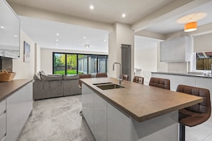A modern kitchen with a central island, seating area, and large windows. - Stylish 4BR Executive Home/Huge Kitchen/Sleeps7 (Bolton)