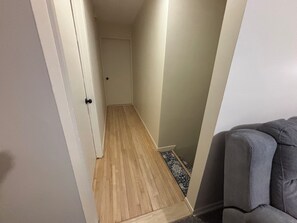 A narrow hallway with wooden flooring and a door at the end. - Top Tier Private Duplex, Centrally Located! (Superior)