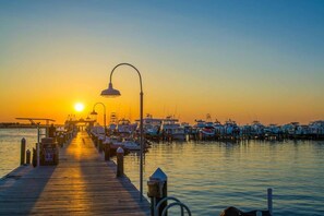 A pier extending into calm water with boats docked at the end, a street lamp, and a clear sky. - Harbour Point 806 (Miramar Beach)