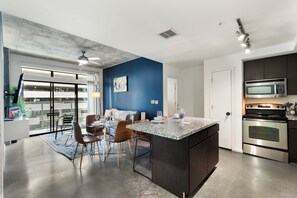 A modern kitchen with a central island, stainless steel appliances, and a blue accent wall. - Classy 2BR | Pool + W/D | Near Arts District (Phoenix)