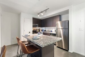 A modern kitchen with a central island, stainless steel appliances, and a granite countertop. - Classy 2BR | Pool + W/D | Near Arts District (Phoenix)