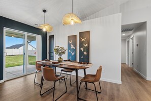 A modern dining area with a wooden table, leather chairs, and pendant lighting. - Boutique Style. Cozy 2BR+ Office for Two. Fenced yard. 30+ days stays. Near I-84 (Nampa)
