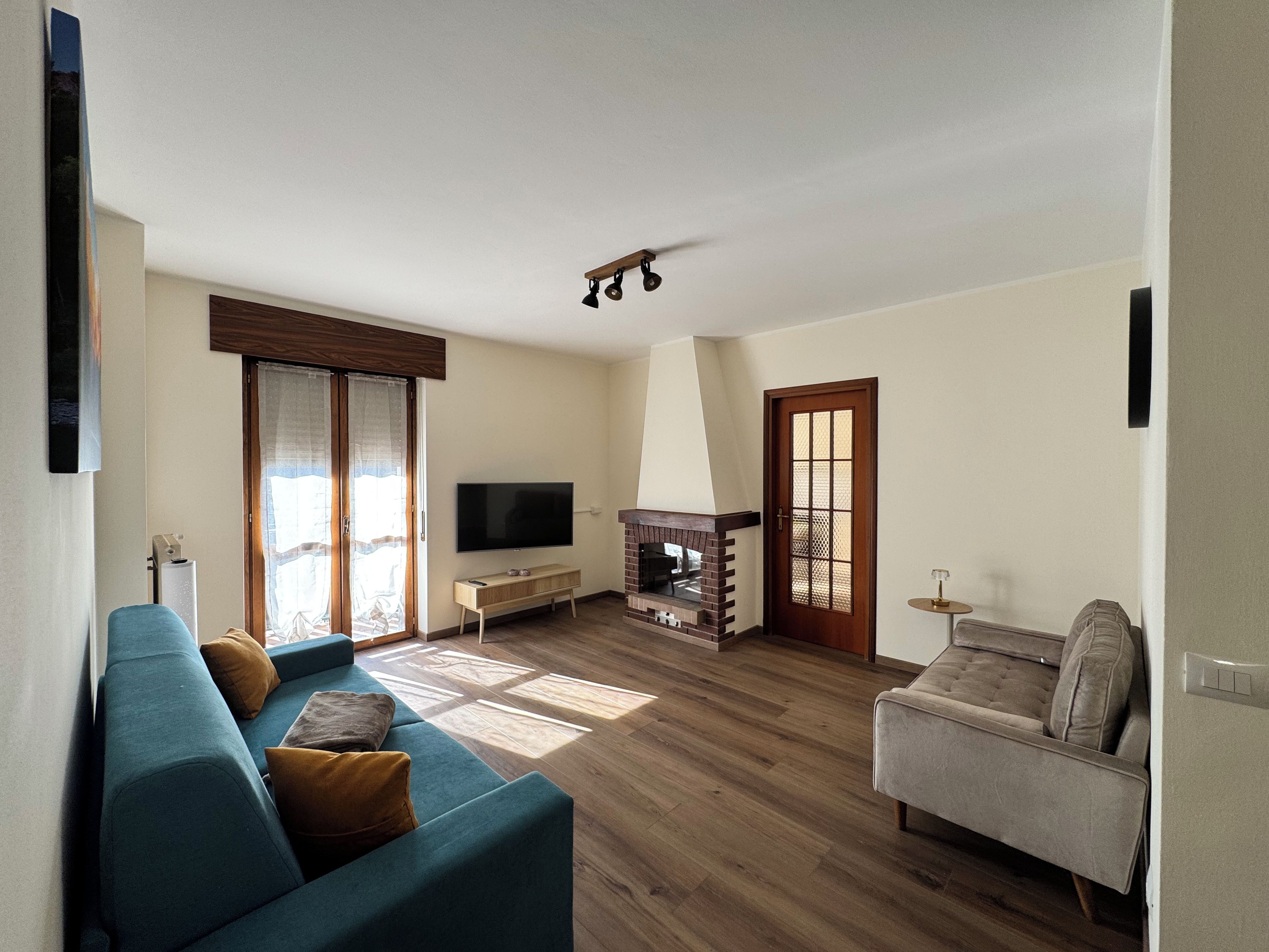 Una sala de estar con sofá, televisión, chimenea y una puerta.