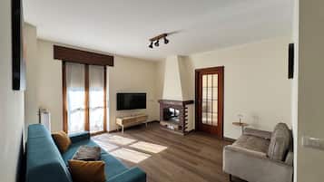 Una sala de estar con sofá, televisión, chimenea y una puerta.