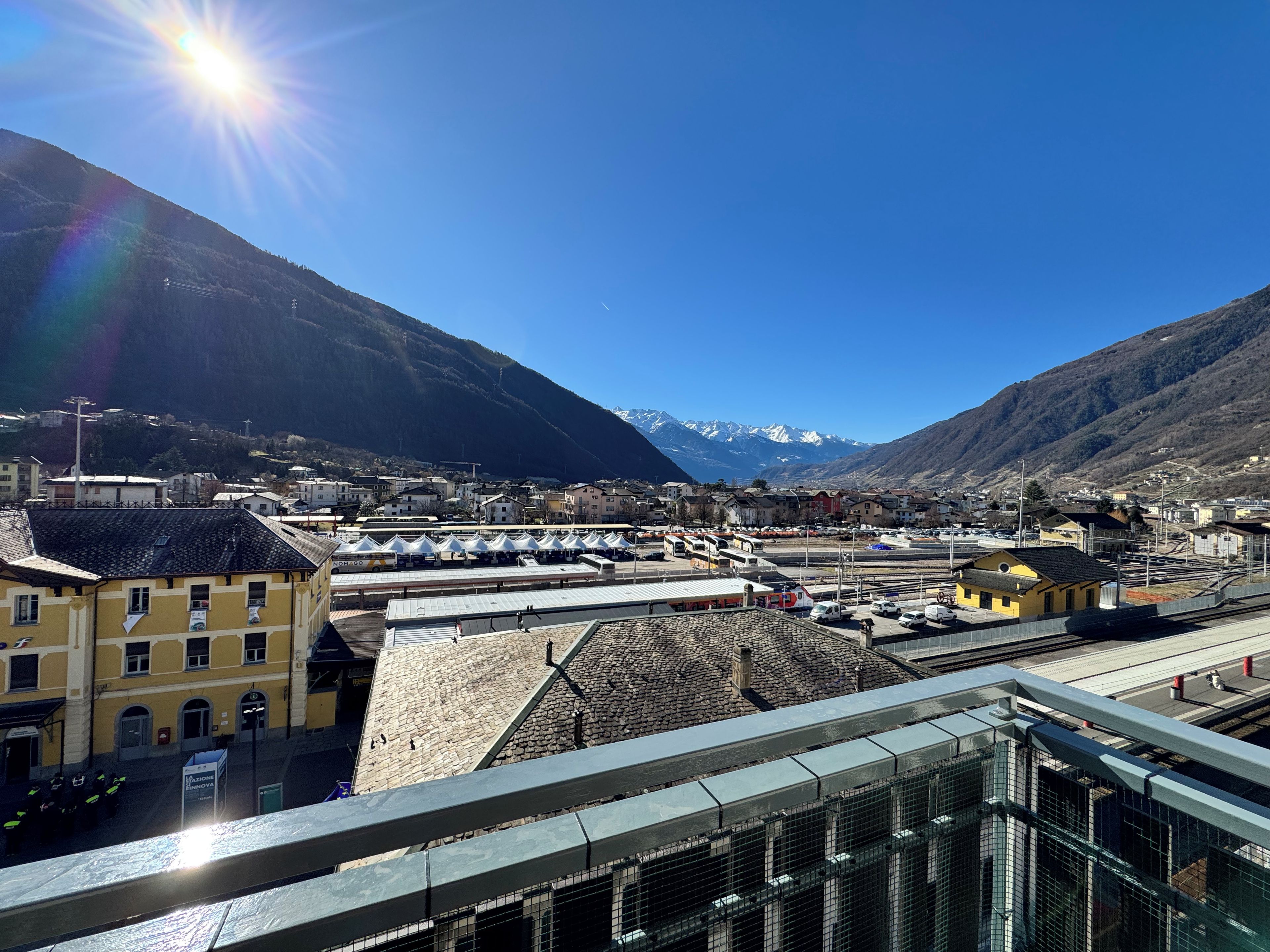 A mountainous town with a clear sky, a train station, and buildings with traditional architecture.