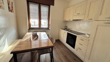 Una cocina compacta con armarios de madera, horno empotrado y una ventana con persianas.