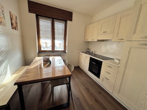 Una cocina compacta con armarios de madera, horno empotrado y una ventana con persianas.