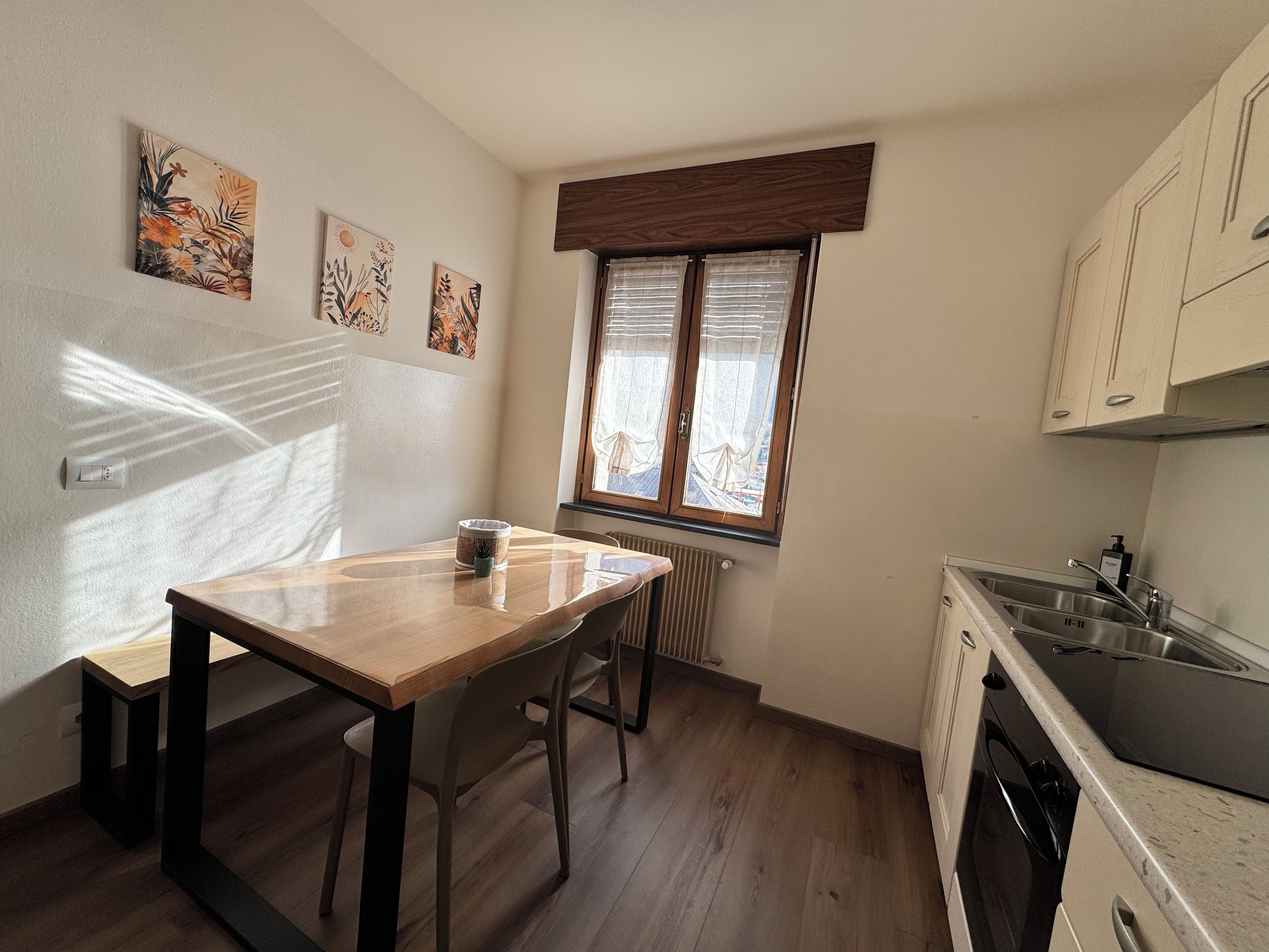 Een keuken met een houten tafel, een raam met zonwering en een radiator.