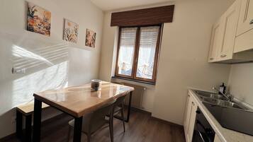 Een keuken met een houten tafel, een raam met zonwering en een radiator.