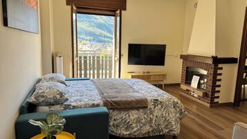 Ein Schlafzimmer mit Bett, Fernseher, Kamin und einem Balkon mit Bergblick.