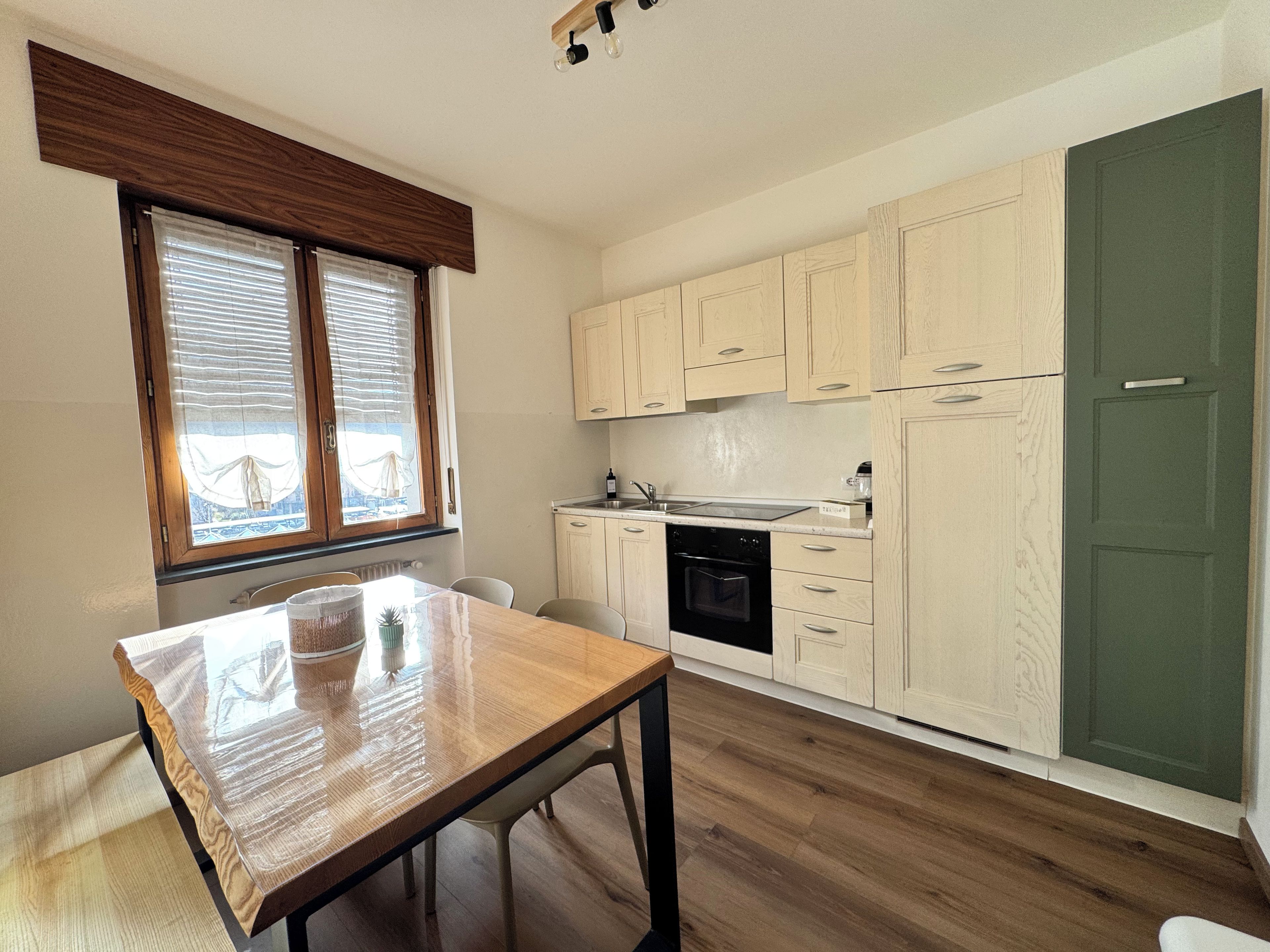 A compact kitchen with wooden cabinets, a built-in oven, and a dining table.