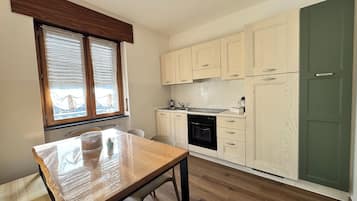 A compact kitchen with wooden cabinets, a built-in oven, and a dining table.