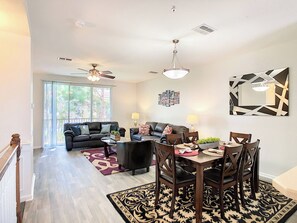 A spacious living room with a dining area, a ceiling fan, and a large window. - Vista Cay Resort Orlando 3 Bed 3,5bath Townhouse (Orlando)
