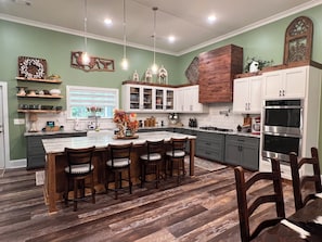 A modern kitchen with a central island, wooden chairs, and a large oven. - Luxury 10-Acre Southern Estate: Perfect for Tournament Groups two living rooms (Wrens)
