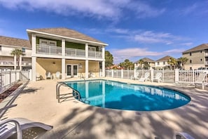 A pool area with a two-story building, lounge chairs, and a fenced swimming pool. - Bonita Circle 206a (Panama City Beach)