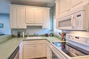 A kitchen with white cabinets, a microwave, an oven, and a coffee maker. - Bonita Circle 206a (Panama City Beach)
